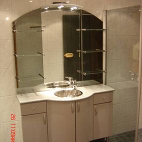 Kylpyhuoneen lavuaari suurella peilillä ja kaapeilla